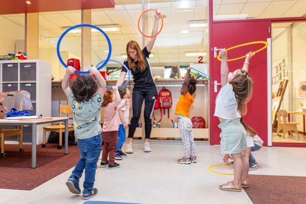 Children and a teacher doing exercises with a hula hoop.